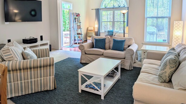A living room with a TV, sofas, a coffee table, and a bookshelf. - Spacious 4BR Forest Landing Duplex - Dog Friendly, Pool & Trails! (Frankford)