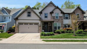A two-story house with a garage, a front porch, and a well-maintained lawn. - Spacious 4BR Forest Landing Duplex - Dog Friendly, Pool & Trails! (Frankford)
