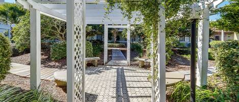 Un sendero en el jardín que conduce a una pérgola con estructura de celosía.