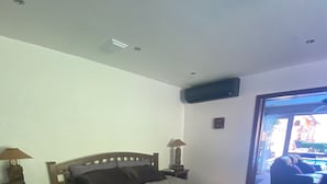 Un dormitorio con cama, mesitas de noche, lámpara, alfombra y vistas al exterior.