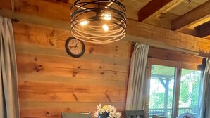 A wooden dining table with six chairs, a vase with flowers, and a hanging light fixture. - O'Connors Retreat - Blowing Rock, Hot tub Secluded acreage, fabulous views (Lenoir)