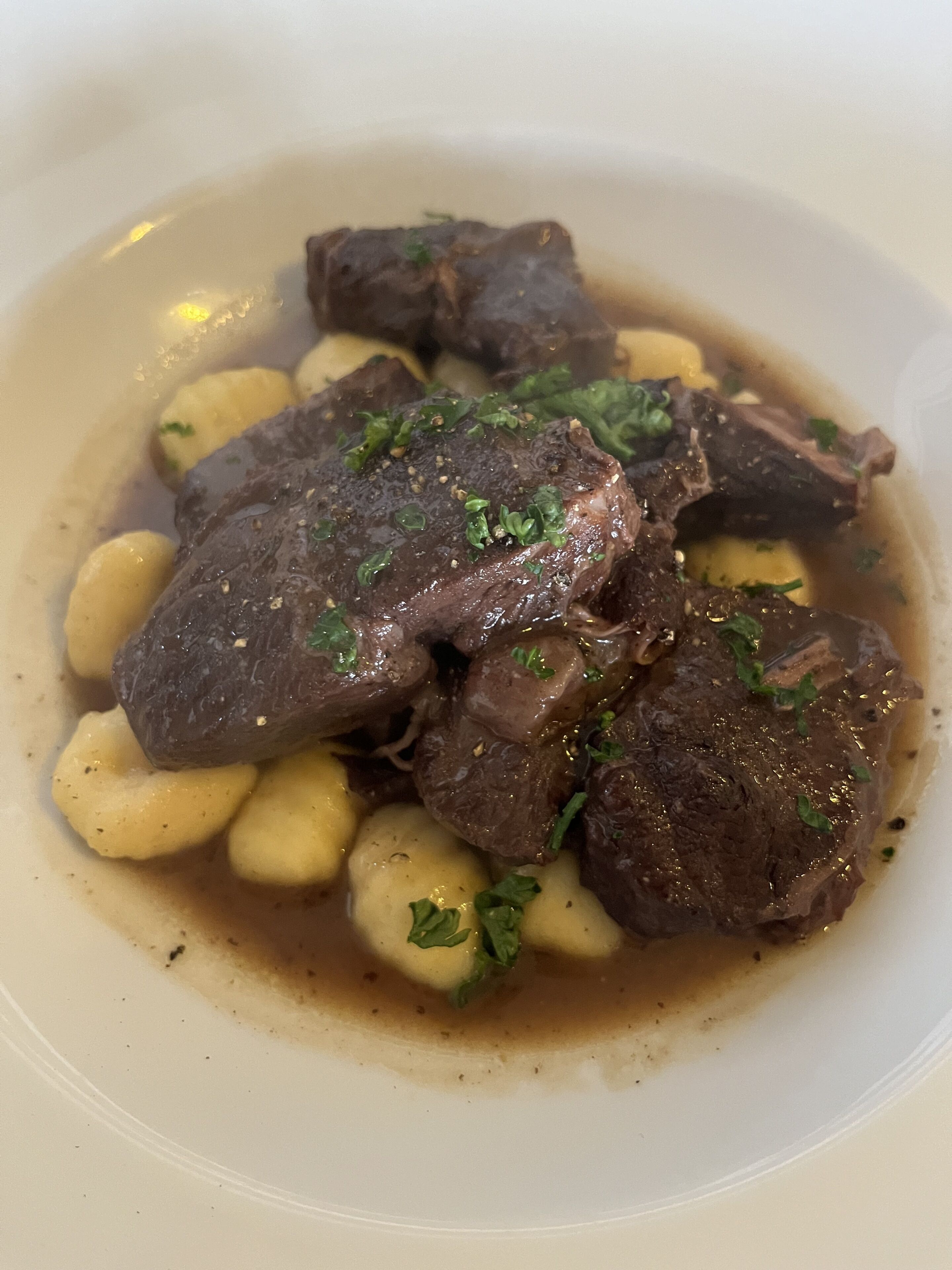 Un bol de bœuf à la sauce, accompagné de pommes de terre et d’herbes aromatiques.
