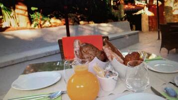 Una tavola apparecchiata per la colazione, con piatti, bicchieri e un cestino di pane.
