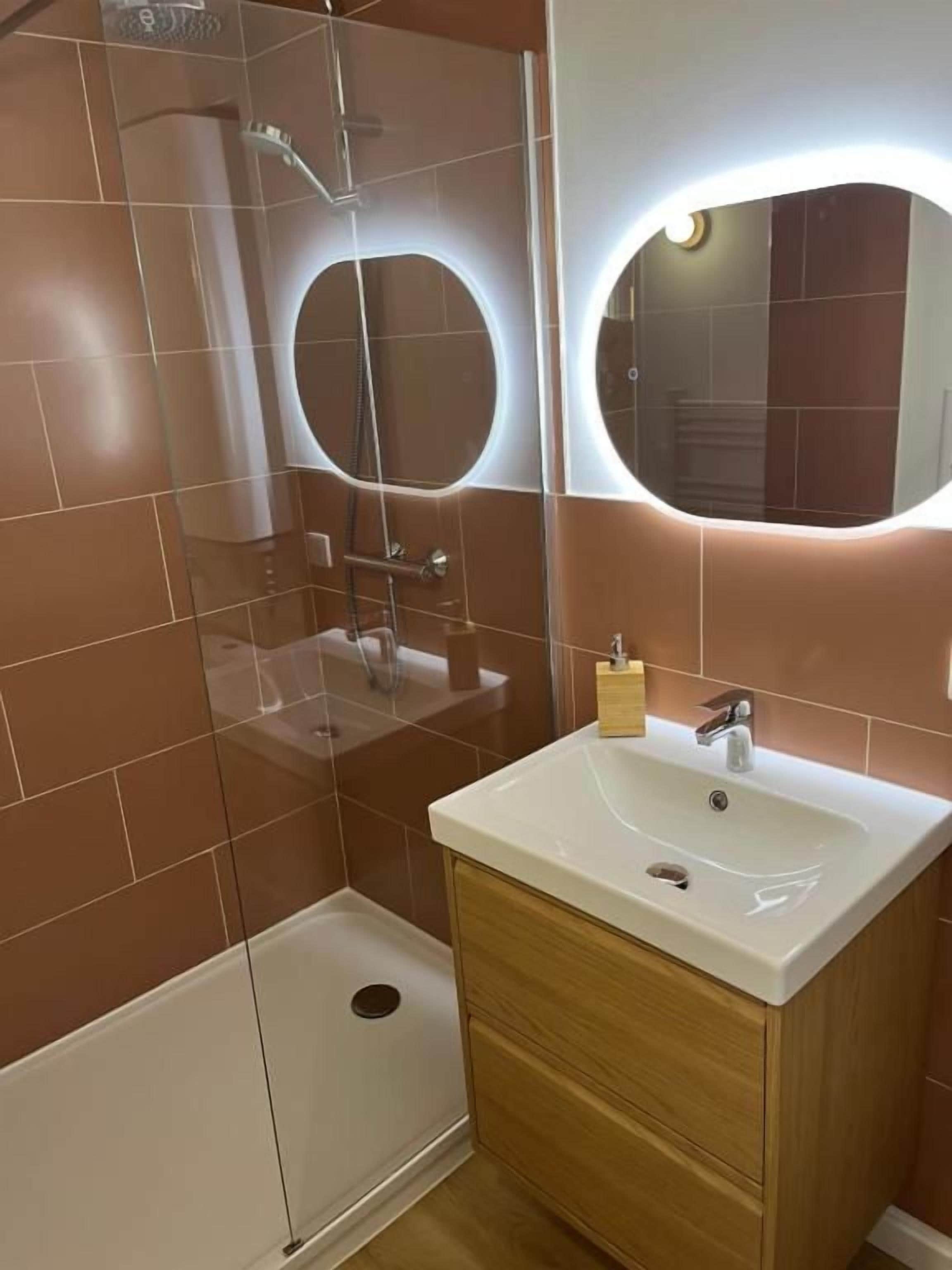 A bathroom with a shower, a sink, and two mirrors.