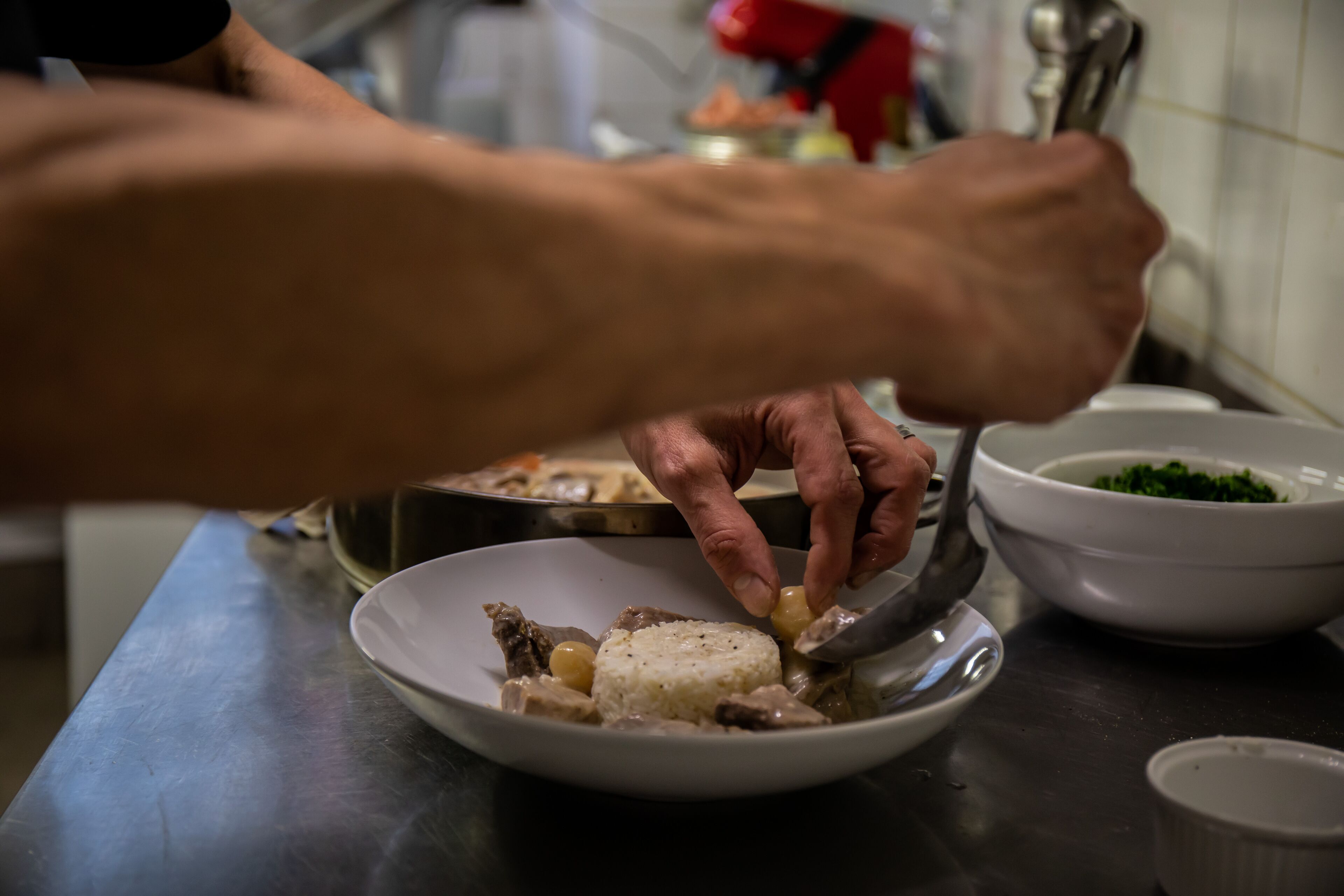 Une personne qui sert du riz et de la viande dans une assiette.