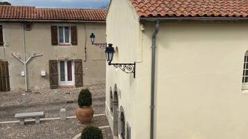 Une cour intérieure avec un bâtiment doté d’un toit recouvert de tuiles, d’une cheminée et d’un petit panneau.