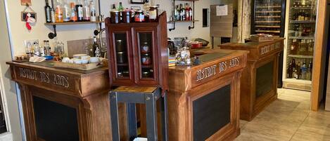 A bar area with wooden counters labeled "BISTROT DES ARTS," shelves with various bottles, and a refrigerator.