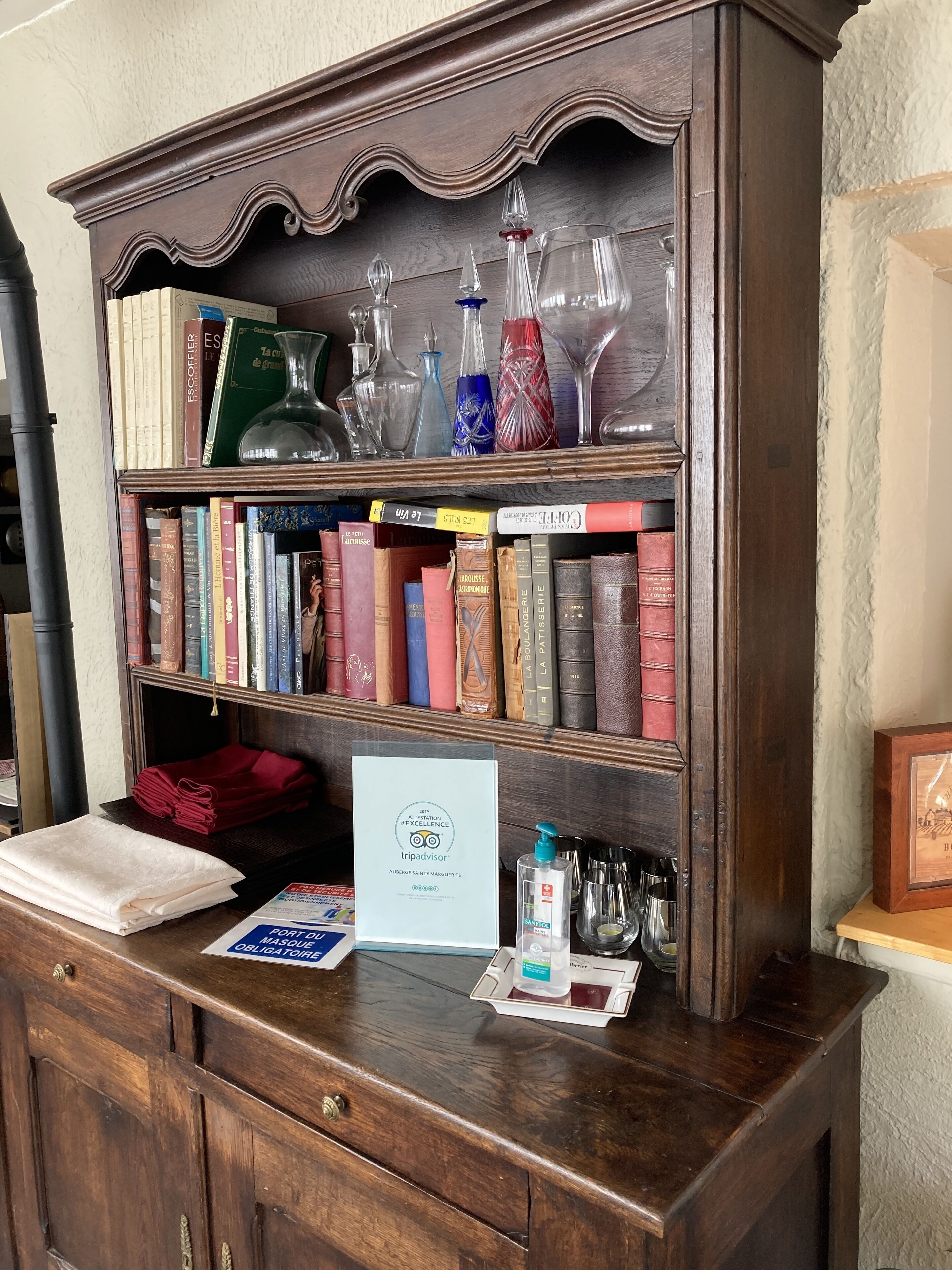 Una estantería de madera con libros y adornos de vidrio.
