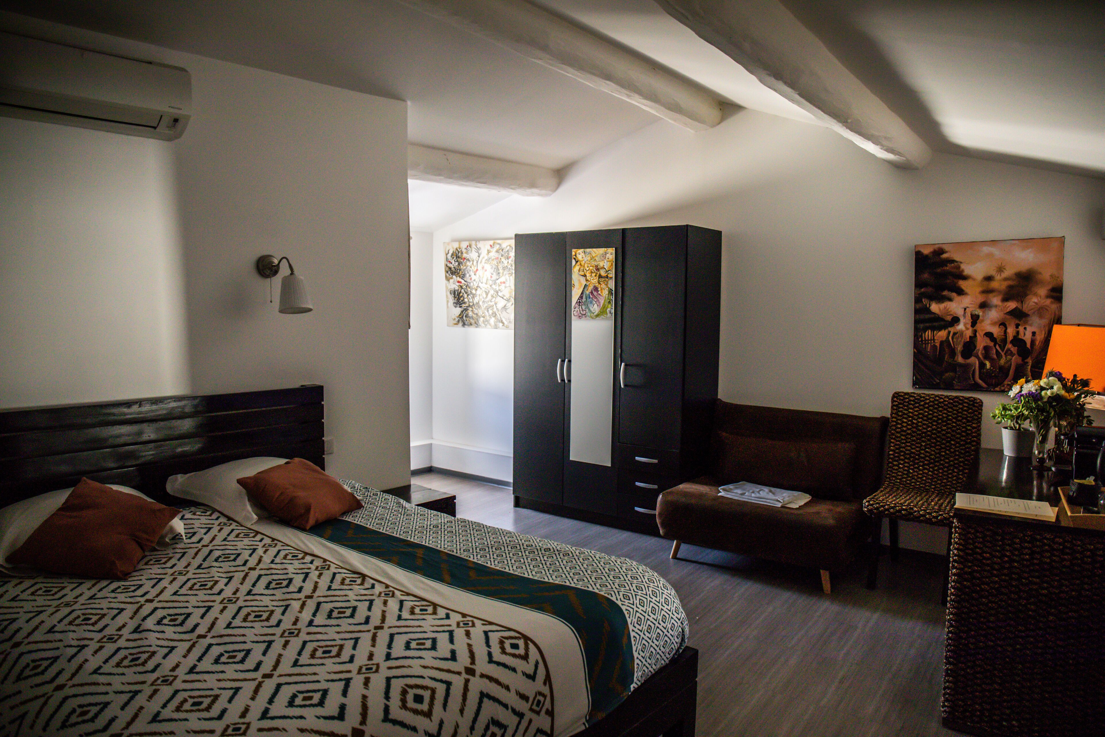 A bedroom with a bed, a wardrobe, a sofa, and a chair.