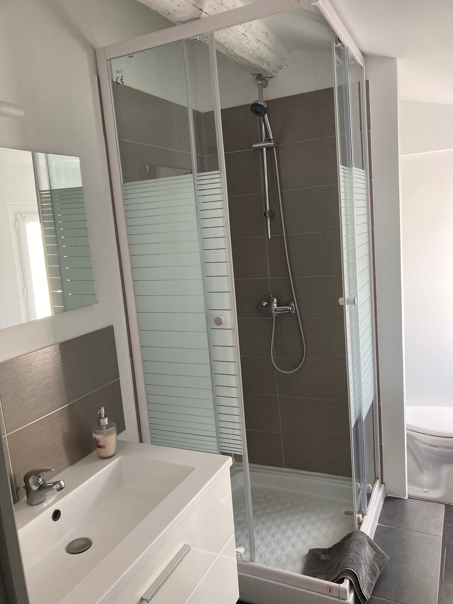 Un baño moderno con ducha de vidrio, lavamanos blanco y retrete.