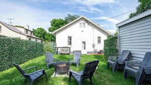 A backyard with a white house, a fire pit, and outdoor furniture. - Downtown Fargo Gem: Full Home for Large Groups (Fargo)