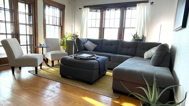 A spacious living room with a sectional sofa, two armchairs, a coffee table, and a potted plant. - Historic Condo in Downtown Fargo (Fargo)