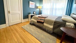 A bedroom with a bed, a desk, a lamp, and a window with curtains. - Historic Condo in Downtown Fargo (Fargo)