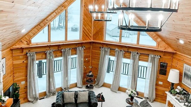 A cozy wooden cabin with a loft bedroom, large windows, and a chandelier. - The Lakefront Lodge near CHQ Institution (Mayville)
