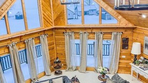 A spacious loft-style room with a high ceiling, large windows, and a cozy seating area with sofas and a coffee table. - The Lakefront Lodge near CHQ Institution (Mayville)