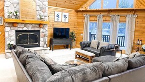 A cozy living room with a stone fireplace, a large flat-screen TV, and a comfortable seating area with sofas and a coffee table. - The Lakefront Lodge near CHQ Institution (Mayville)