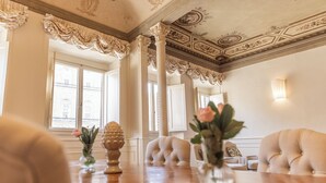 Een kamer met een houten tafel, crèmekleurige stoelen en een decoratief plafond.