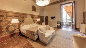 Een slaapkamer met een groot bed, twee nachtkastjes, een bank, een televisie en uitzicht buiten.