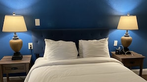 Un dormitorio con una cama grande, dos mesitas de noche con lámparas y una pared azul.
