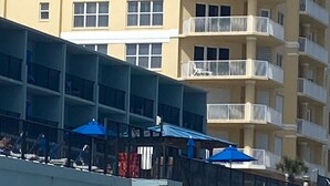 Un hotel frente a la playa con varios balcones, un letrero que dice Dolphin Beach Club y sombrillas de playa.