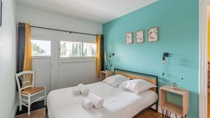 Ein Schlafzimmer mit Bett, Stuhl, Nachttisch und einem Fenster mit Vorhängen.