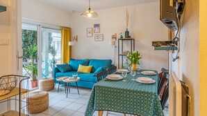 Ein Essbereich mit Tisch für vier Personen, einem blauen Sofa und einer Deckenleuchte.