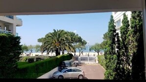 Blick aus einem Fenster auf einen Parkplatz mit einer Palme und einem Gebäude im Hintergrund.