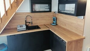 Eine kleine Küche mit einer Holzarbeitsplatte, schwarzen Schränken, einer eingebauten Spüle und einer Kaffeemaschine.