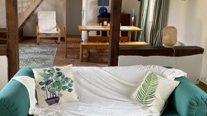Un salon chaleureux avec un canapé vert, une table en bois et un escalier.