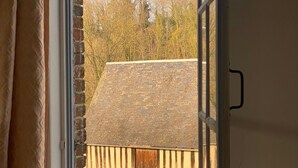 Une fenêtre donnant sur un bâtiment en briques et une cour verdoyante.