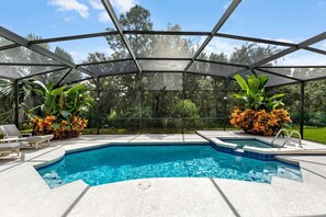 A covered outdoor swimming pool with lounge chairs and tropical plants. - Murano Mews (Kissimmee)