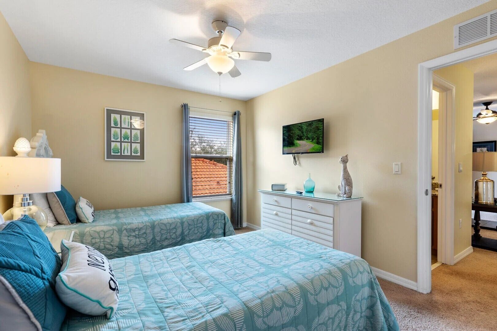 A bedroom with two beds, a ceiling fan, a TV, and a dresser.