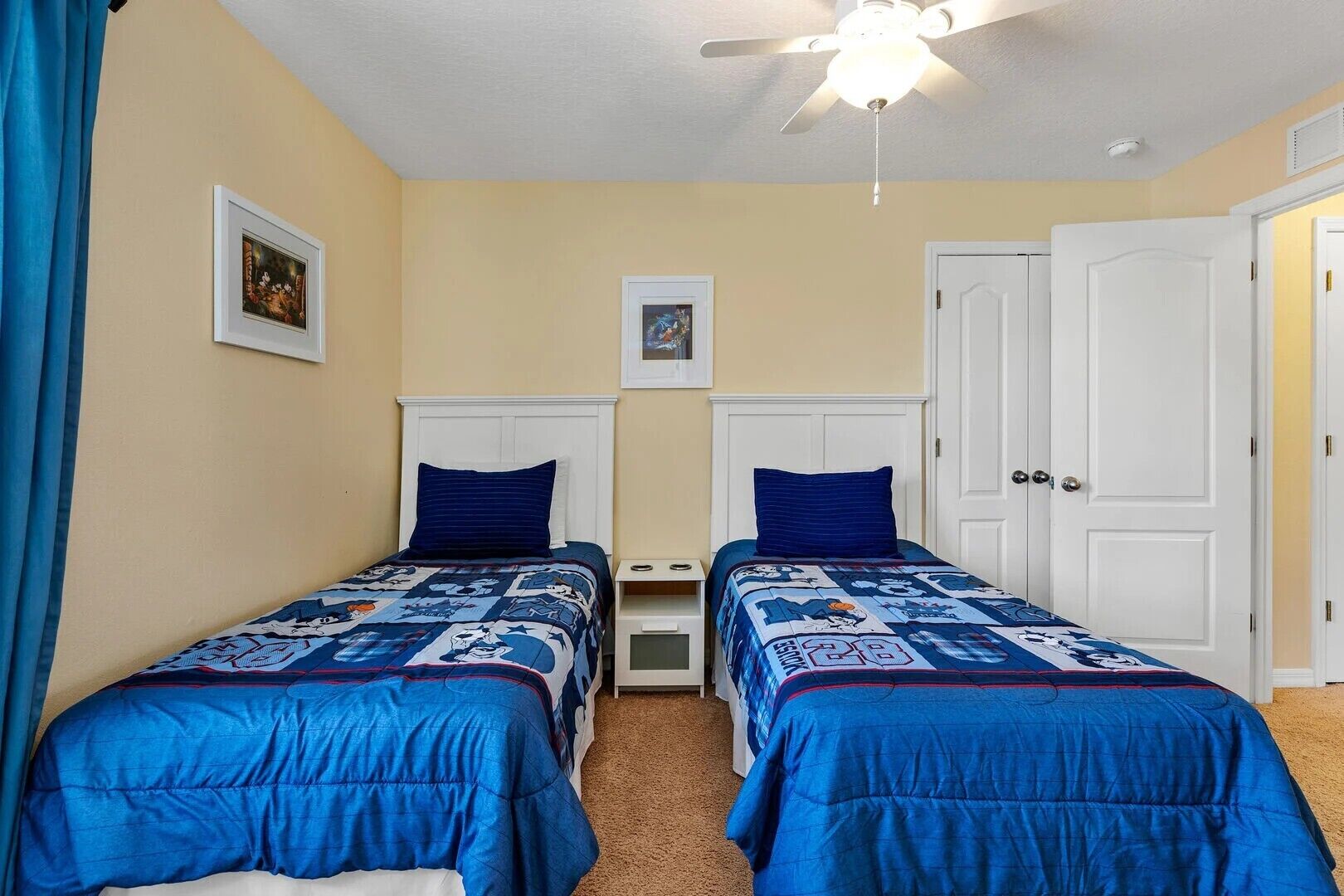 Een slaapkamer met twee eenpersoonsbedden, een plafondventilator en een deur.