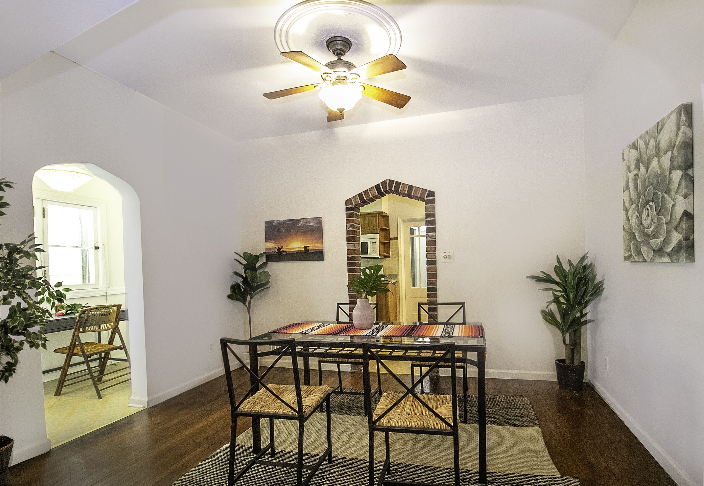 Un coin repas comprenant une table ronde, des chaises, un ventilateur de plafond et un miroir.