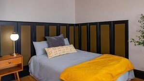 A bedroom with a bed, a nightstand, a lamp, and a plant. - Amazing Uptown Studio long stays (Minneapolis)