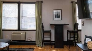 A room with a black desk, two chairs, a round table, and a framed picture on the wall. - Amazing Uptown Studio long stays (Minneapolis)