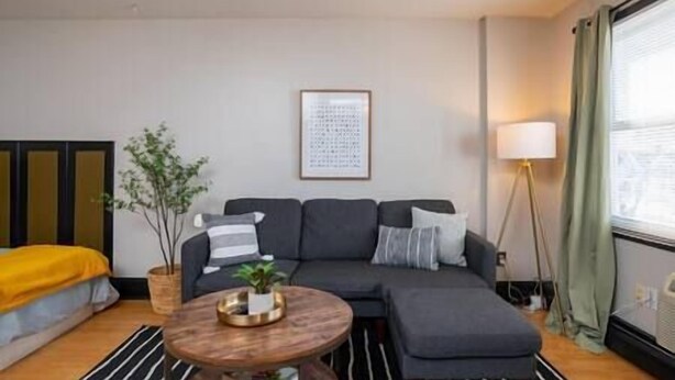 A modern living room with a sofa, a coffee table, and a lamp. - Amazing Uptown Studio long stays (Minneapolis)