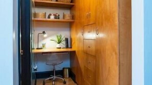 A compact kitchen with wooden cabinets, a built-in shelf, a small desk, and a chair. - Amazing Uptown Studio long stays (Minneapolis)