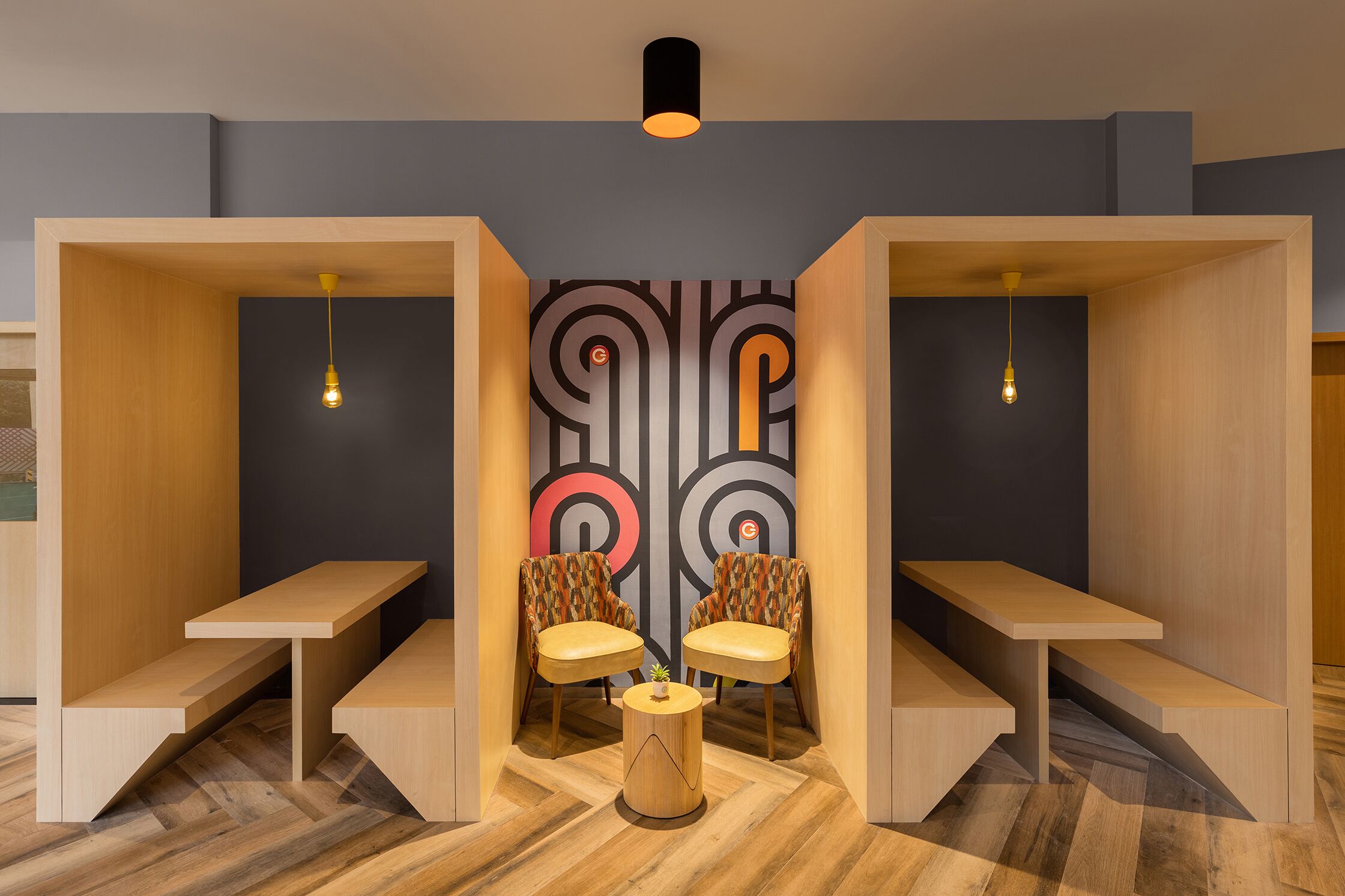 Una habitación moderna con dos bancos de madera, una mesita redonda y dos sillas con tapicería estampada.