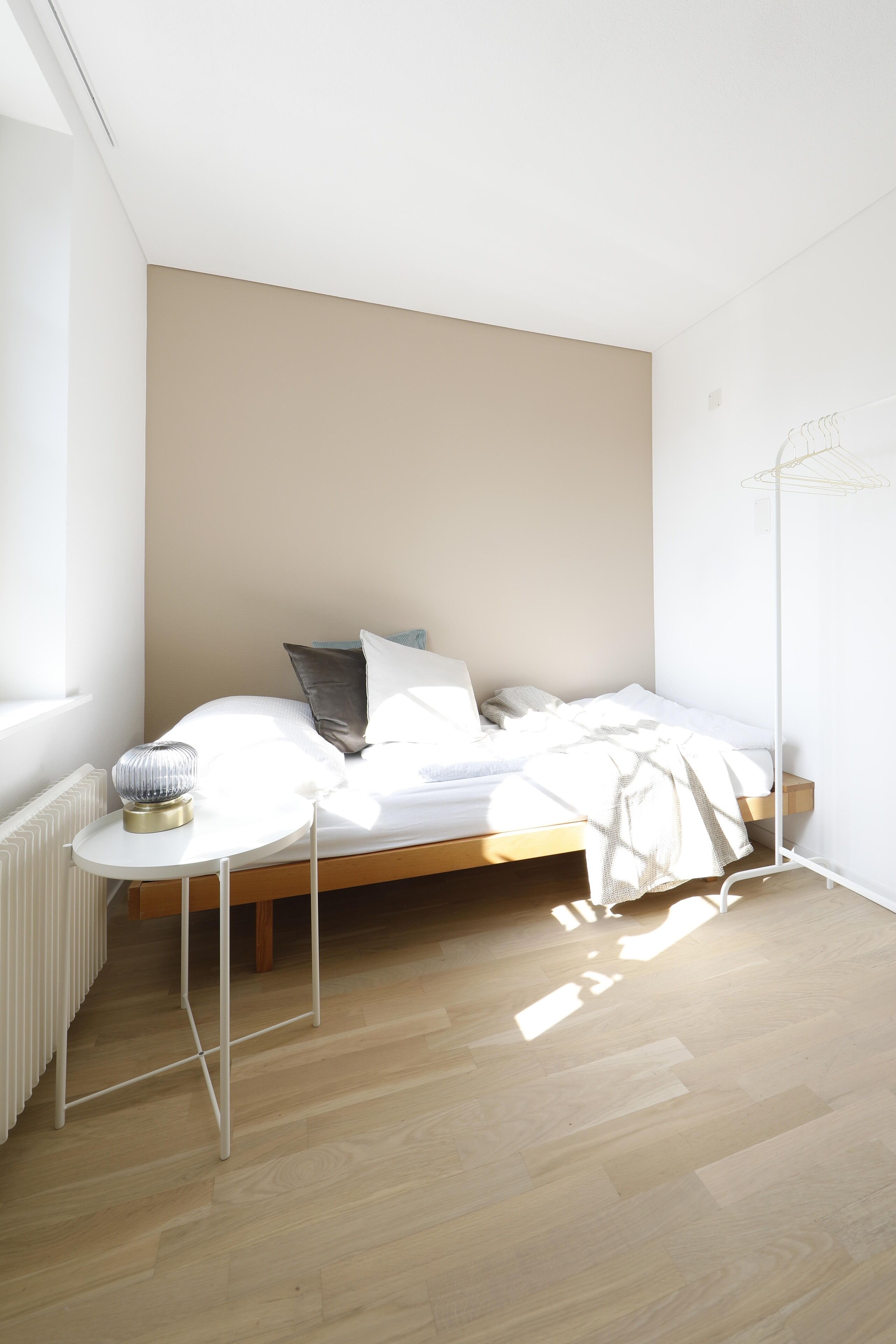 A minimalist bedroom with a bed, bedside table, and a floor lamp.