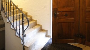 A staircase with a wooden handrail leading to a door with a metal decorative arch. - Hotel Untertor by Maier Self-Check-in (Altstaetten)
