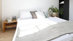 A minimalist bedroom with a large bed, a bedside table with a lamp, and a potted plant. - Hotel Untertor by Maier Self-Check-in (Altstaetten)