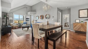 A spacious living room with a large dining table, comfortable seating, and a view of the outdoors. - Luxury | Comfort | Pool | Hot Tub | Gym (Invermere)