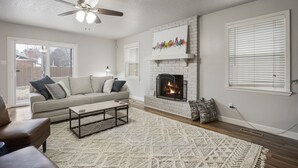 A living room with a fireplace, a ceiling fan, and a sofa. - Charming 3bed/2 bath near Gathering Place, Riverparks and Downtown (Tulsa)