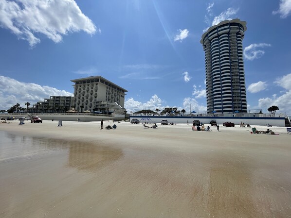 A beach with a high-rise hotel and a tall building in the background.