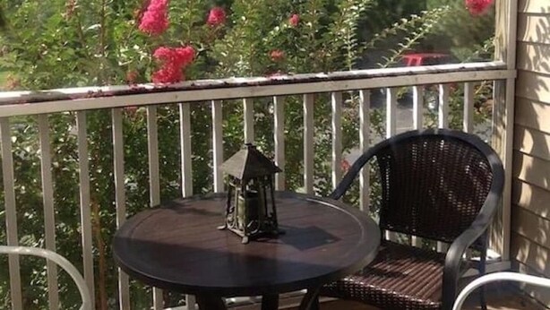 A balcony with a round table and two chairs, surrounded by a white railing. - Reasonable  Rates: Beautiful Condo Close to Beach, Restaurants, Shopping & More! (Rehoboth Beach)