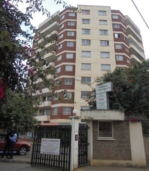 Een meerlaags appartementencomplex met een bord waarop 'Dhanjay Apartments' staat.
