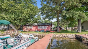 Un muelle con barcos, una casa roja y un muro de piedra.