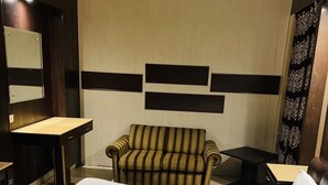 A hotel room with a bed, a sofa, a desk, and a mirror. - Hotel R S Residency (Amritsar)