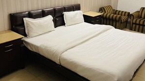 A neatly made bed with white linens, a dark headboard, and two bedside tables with drawers. - Hotel R S Residency (Amritsar)
